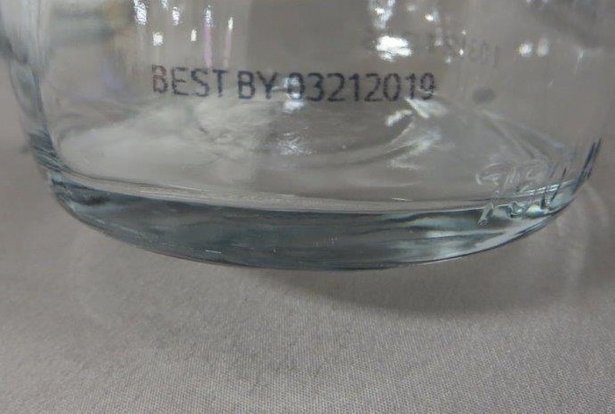 Expiry date code on clear glass bottle, mark made with MMS inkjet 
