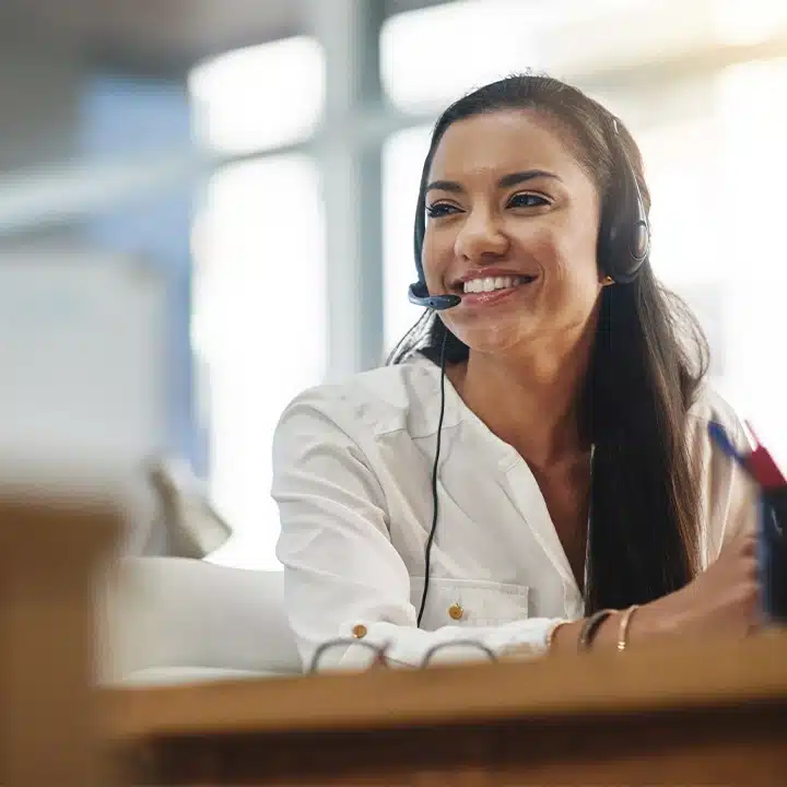 Customer support team member assisting a customer while wearing a headset in a modern office environment.