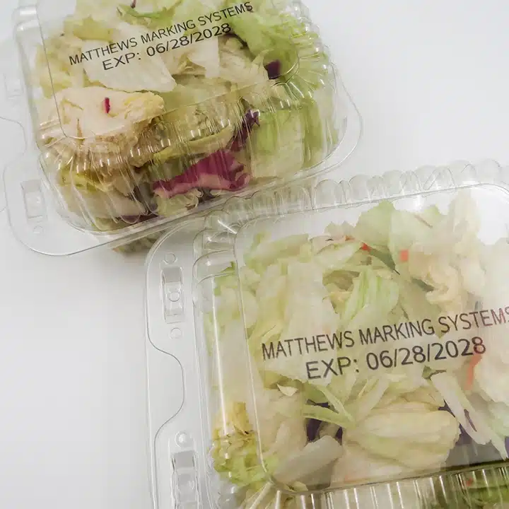 Fresh produce clamshell containers printed with expiration dates for food packaging traceability.