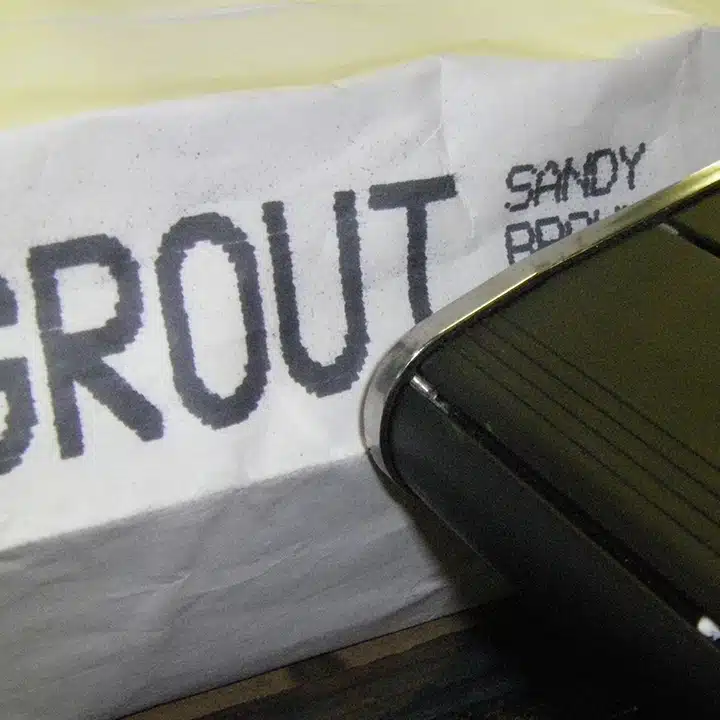 V-Series DOD printer that is printing the word Grout in large letters in black ink on a white bag.