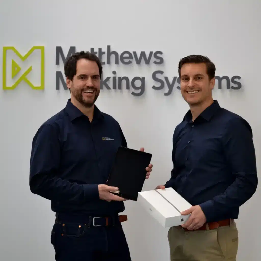smiling employee and chef in front of firm logo