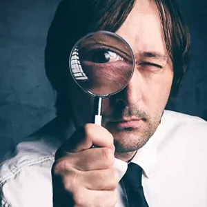 Man looking through a magnifying glass, representing close inspection of barcode print quality, readability, and verification accuracy.