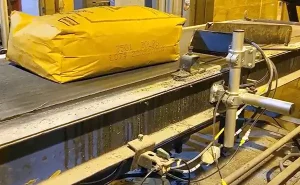 Yellow industrial package with printed identification codes traveling along a conveyor in a manufacturing facility.
