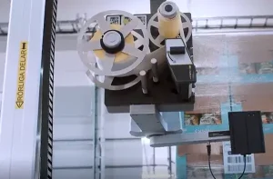 Automated print-and-apply labeling system applying a barcode label to a palletized load of packaged products.