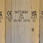 Wooden lumber board printed with UKCA and CE conformity symbols, Matthews identification codes, and additional product information.